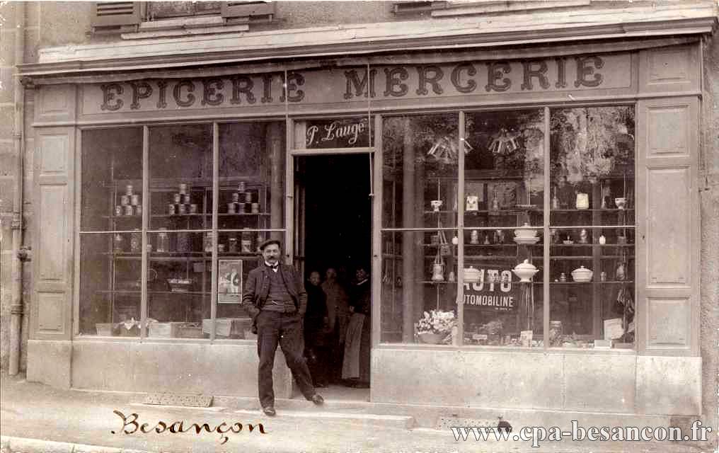 Homme posant devant une épicerie mercerie..